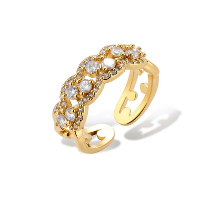 Adjustable gold-plated ring with multiple crystal clusters in intricate chain design on cream background.
